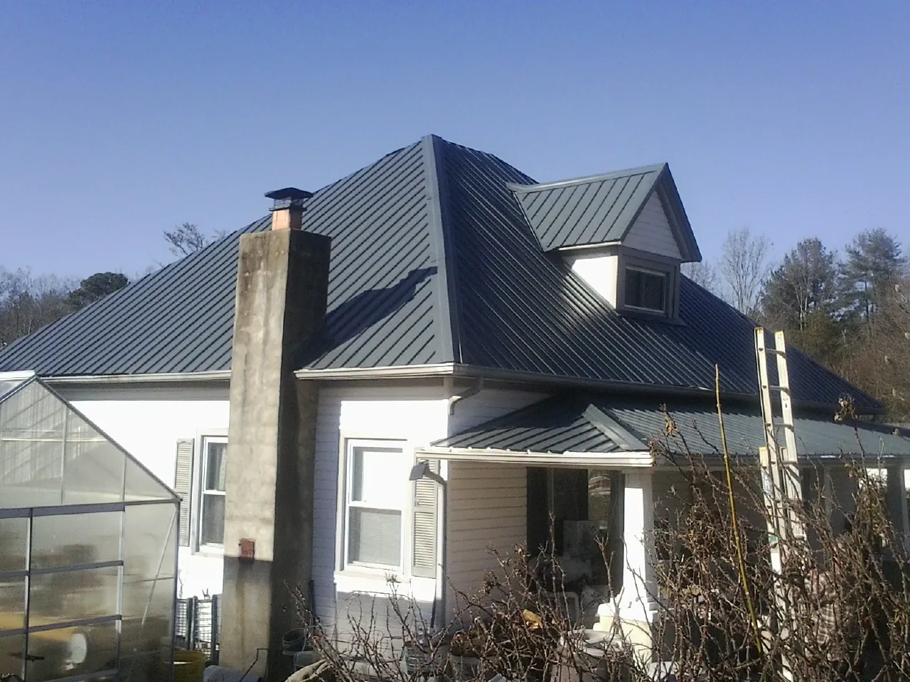 Dark blue standing seam metal roof on a white farmhouse with dormer — Slate & Tile Roof Repair by Roofing Brothers in Etna