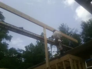 Carpenter setting a ridge beam over a new addition frame — Ice Dam Removal by Roofing Brothers in Etna